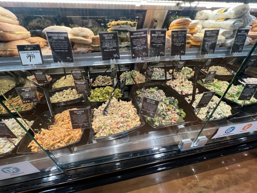 Prepared foods counter at Kowalski’s Market featuring salads, pasta, sandwiches, and breakfast items.